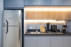 A modern kitchen with a stainless steel refrigerator, a built-in oven, a sink, and a wooden countertop. - Zahle Jardins (São Paulo)