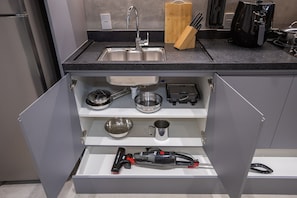 A kitchen with a built-in sink, a coffee maker, and a vacuum cleaner in a drawer.