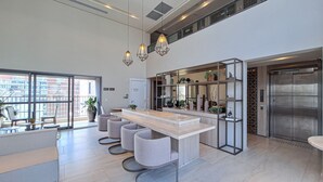 Una cocina moderna con una isla central, iluminación colgante y vistas a la ciudad a través de amplios ventanales.