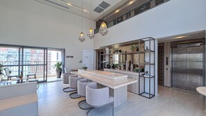 A modern kitchen with a central island, pendant lighting, and a view of the cityscape through large windows. - Zahle Jardins (São Paulo)