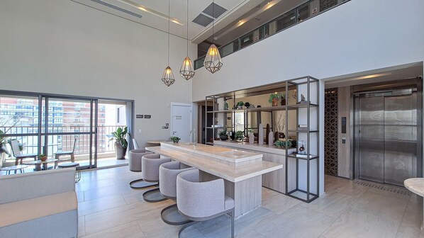A modern kitchen with a central island, pendant lighting, and a view of the cityscape through large windows.