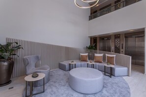 A modern lobby with a seating area, a large potted plant, and an elevator.