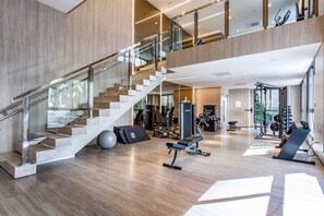 A multi-level gym with a staircase, exercise equipment, and a large window. - Zahle Jardins (São Paulo)