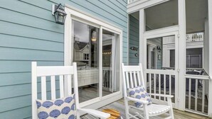 A porch with two white rocking chairs, a wooden stool, and a large window. - Grand Pavilion 34 by Wild Dunes, Luxury Home (Isle of Palms)