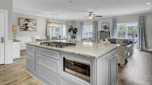 A spacious kitchen with a large island, built-in oven, and a ceiling fan. - Grand Pavilion 34 by Wild Dunes, Luxury Home (Isle of Palms)