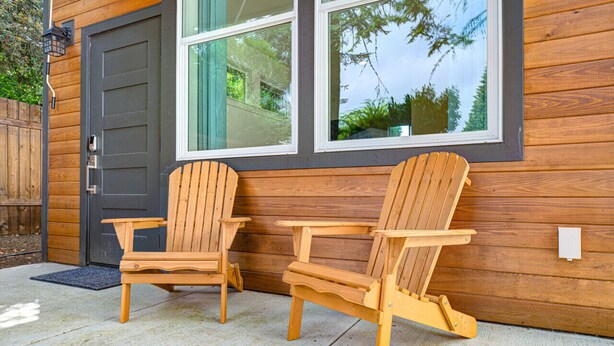 Two wooden Adirondack chairs outside a house with a dark door and large windows reflecting trees. - Urban-chic Studio Guesthouse in a quiet neighborhood - near Intel and Nike (Hillsboro)