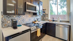 A modern kitchen with dark wooden cabinets, a stainless steel microwave, a gas stove, and a dishwasher. - Urban-chic Studio Guesthouse in a quiet neighborhood - near Intel and Nike (Hillsboro)