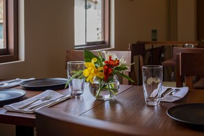 A dining table with a vase of flowers, clear glasses, and neatly arranged cutlery. - Inkantari Boutique Hotel (Cusco)