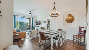 A spacious dining area with a chandelier, a dining table, and chairs.