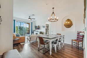 A spacious dining area with a chandelier, a dining table, and chairs.