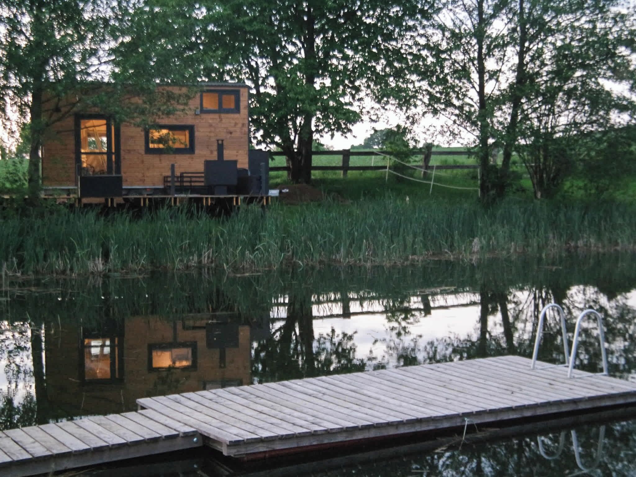 A small cabin with a dock, surrounded by water and trees.