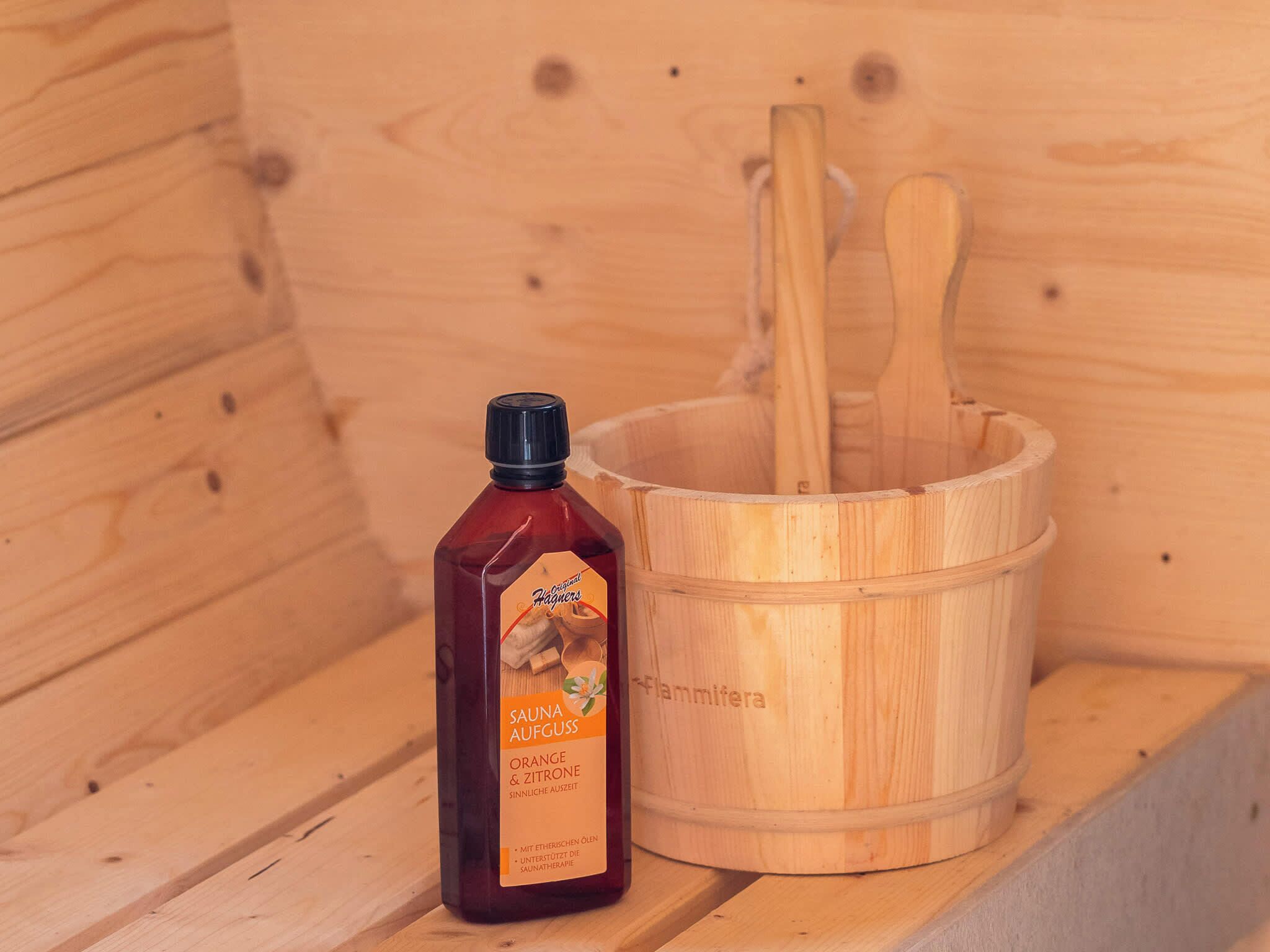 Una sauna de madera con una botella de aceite de naranja y limón, y cucharas de madera.