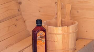 Una sauna de madera con una botella de aceite de naranja y limón, y cucharas de madera.