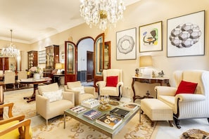 A spacious living room with a chandelier, armchairs, a coffee table with books, and framed artwork on the walls. - 16th-century villa for 14, near Valencia | Villa Paula (Manises)