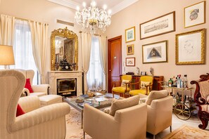 A classic interior with a fireplace, elegant furniture, and a collection of framed artworks on the walls.