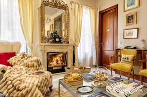 A cozy living room with a fireplace, a large mirror, and a comfortable chair.