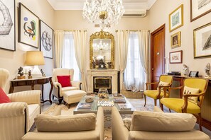 Un salon élégant, doté d’une cheminée, de sièges confortables et d’un lustre.