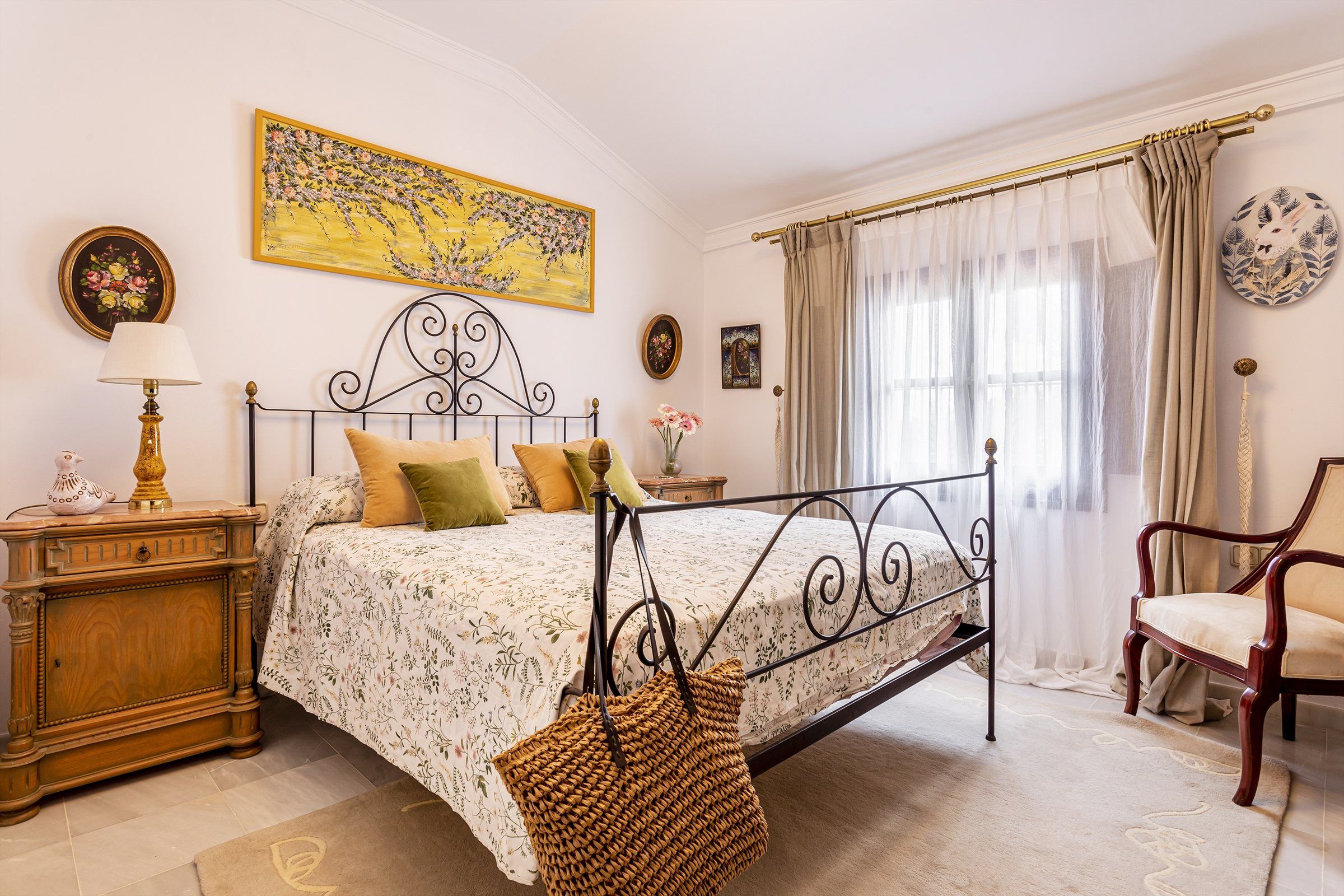 Un dormitorio con una cama con dosel, una mesita de noche de madera, una lámpara, una silla y una ventana con cortinas.