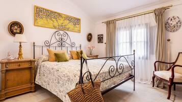 Un dormitorio con una cama con dosel, una mesita de noche de madera, una lámpara, una silla y una ventana con cortinas.