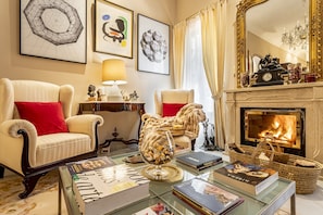 Una sala de estar acogedora con dos sillones, una chimenea y una mesa de centro con libros.