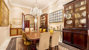 Een stijlvolle eetzaal met een houten tafel, stoelen, een kroonluchter en een vitrinekast.