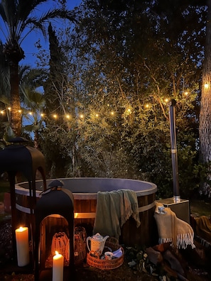 Un jacuzzi rodeado de árboles, con luces de cuerda y velas.