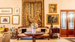 Una habitación con un tapiz grande y ornamentado, un sofá, una mesita de café y un mueble de madera.