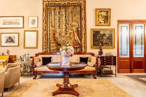 Una habitación con un tapiz grande y ornamentado, un sofá, una mesita de café y un mueble de madera.