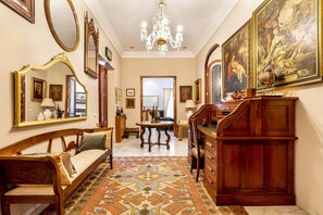 Una habitació amb un sofà de fusta, una taula de menjador, una làmpada penjant i un quadre gran a la paret.
