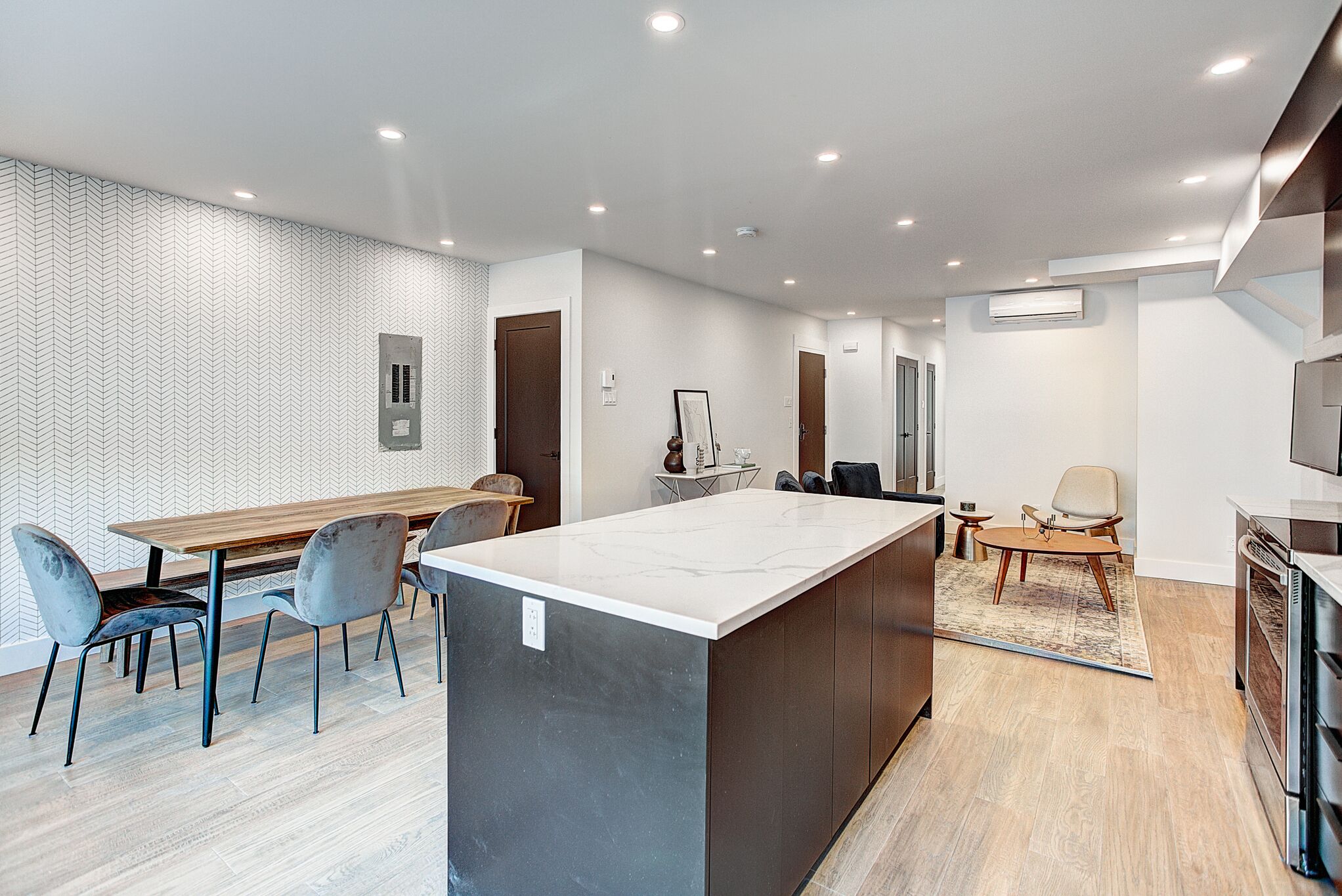 A modern kitchen with a central island, a dining area with chairs, and a kitchen island with a chair.