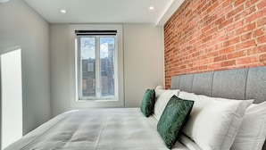 Un dormitorio con una cama grande, una pared de ladrillo y una ventana.