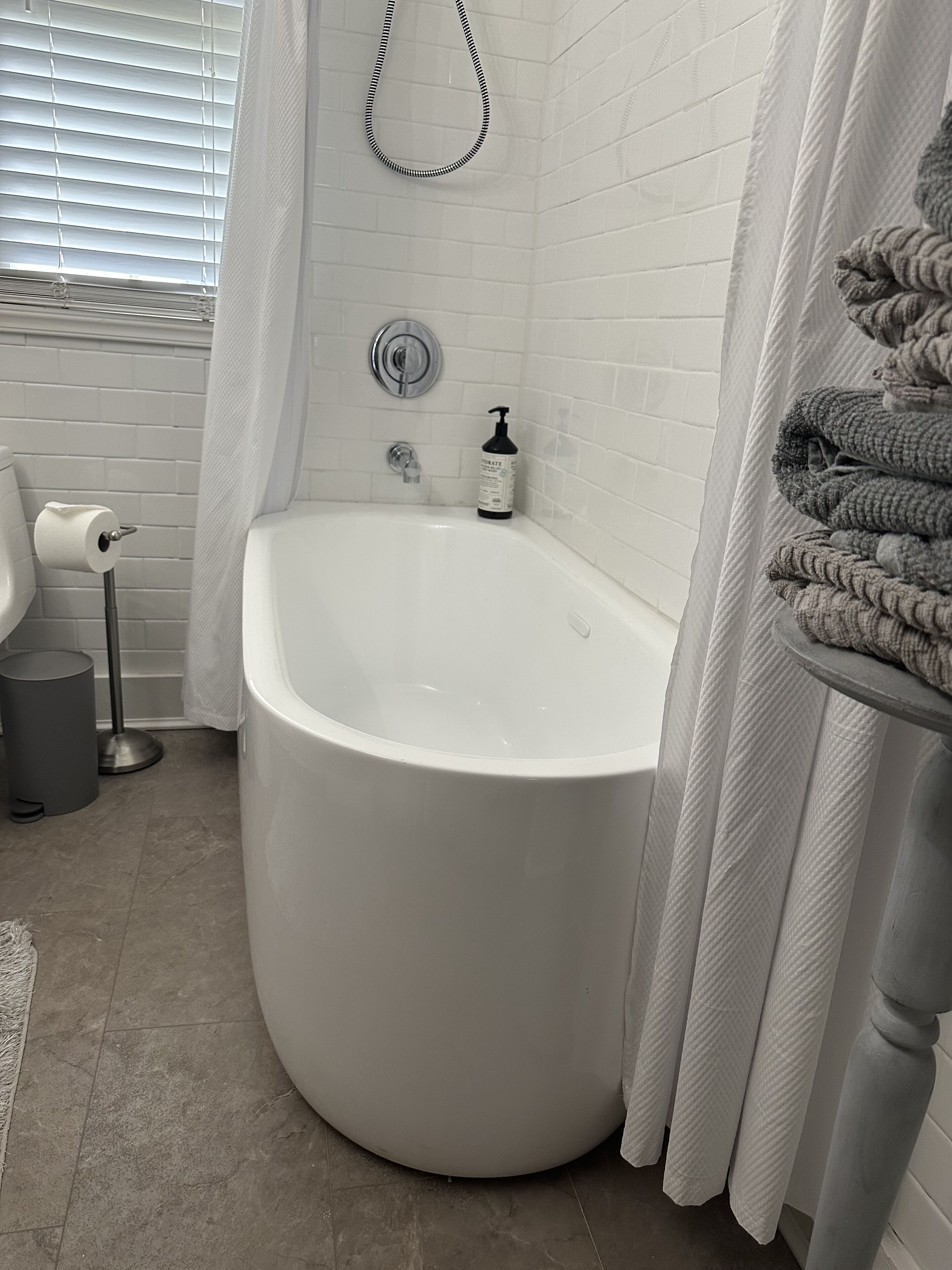 A bathroom with a large bathtub, a toilet, and a towel rack.