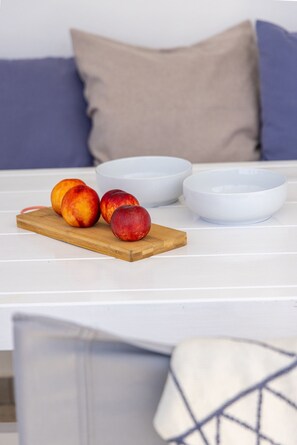 A wooden cutting board with peaches on a white table. - Anemelo Beach House in Panormos (Tinos)