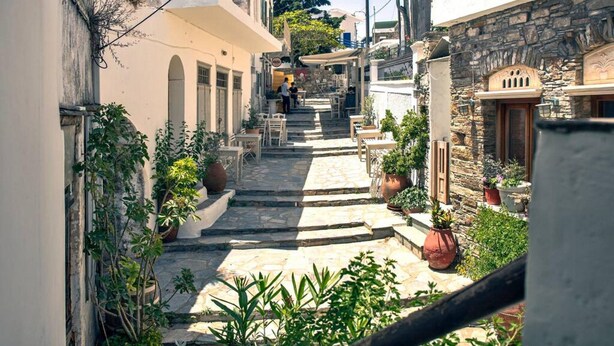 Uma rua estreita com degraus de pedra que levam a um edifício com mesas ao ar livre.