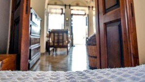 Visão do interior de um corredor com portas de madeira e piso branco texturizado.