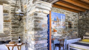 A rustic stone-walled room with a bed, a desk, and a chair. - Delphis the Artist s House (Tinos)