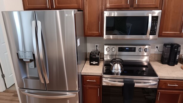A kitchen with stainless steel appliances including a refrigerator, microwave, and stove. - Paradise Village home in perfect golfing and recreation center location.  (The Villages)