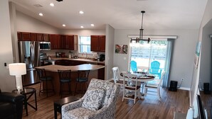 A modern kitchen with wooden cabinets, a stainless steel refrigerator, and a central island with bar stools. - Paradise Village home in perfect golfing and recreation center location.  (The Villages)