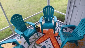 A covered patio area with turquoise chairs and a starfish-patterned rug. - Paradise Village home in perfect golfing and recreation center location.  (The Villages)
