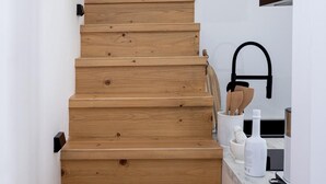 Puinen portaikko johtaa keittiötilaan, jossa on moderni hana ja keittiövälineet.