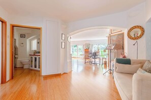A spacious living area with a dining table, a sofa, and a kitchen in the background.