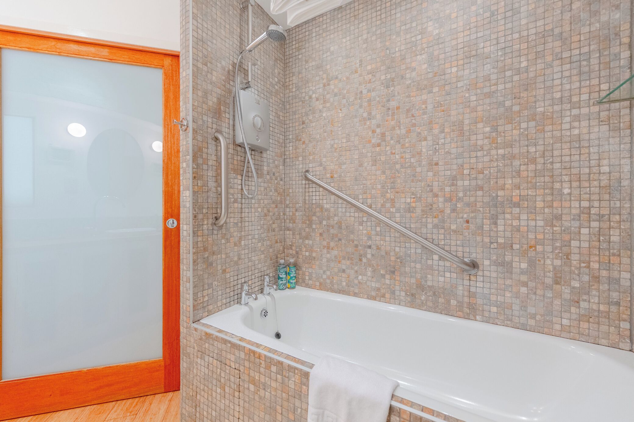 A bathroom with a shower, a bathtub, and a glass door.