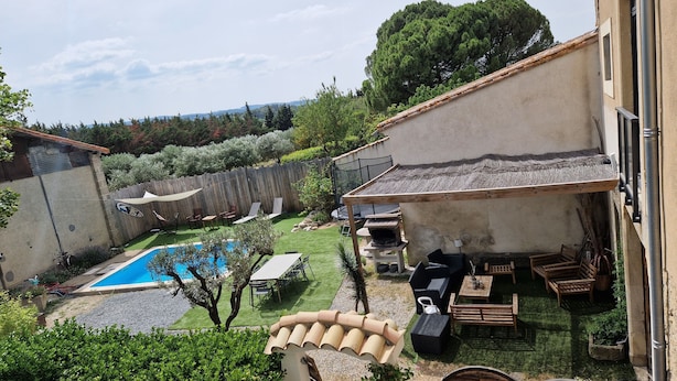 Ein Garten mit Swimmingpool, Sitzgelegenheiten im Freien und einer Grillanlage.