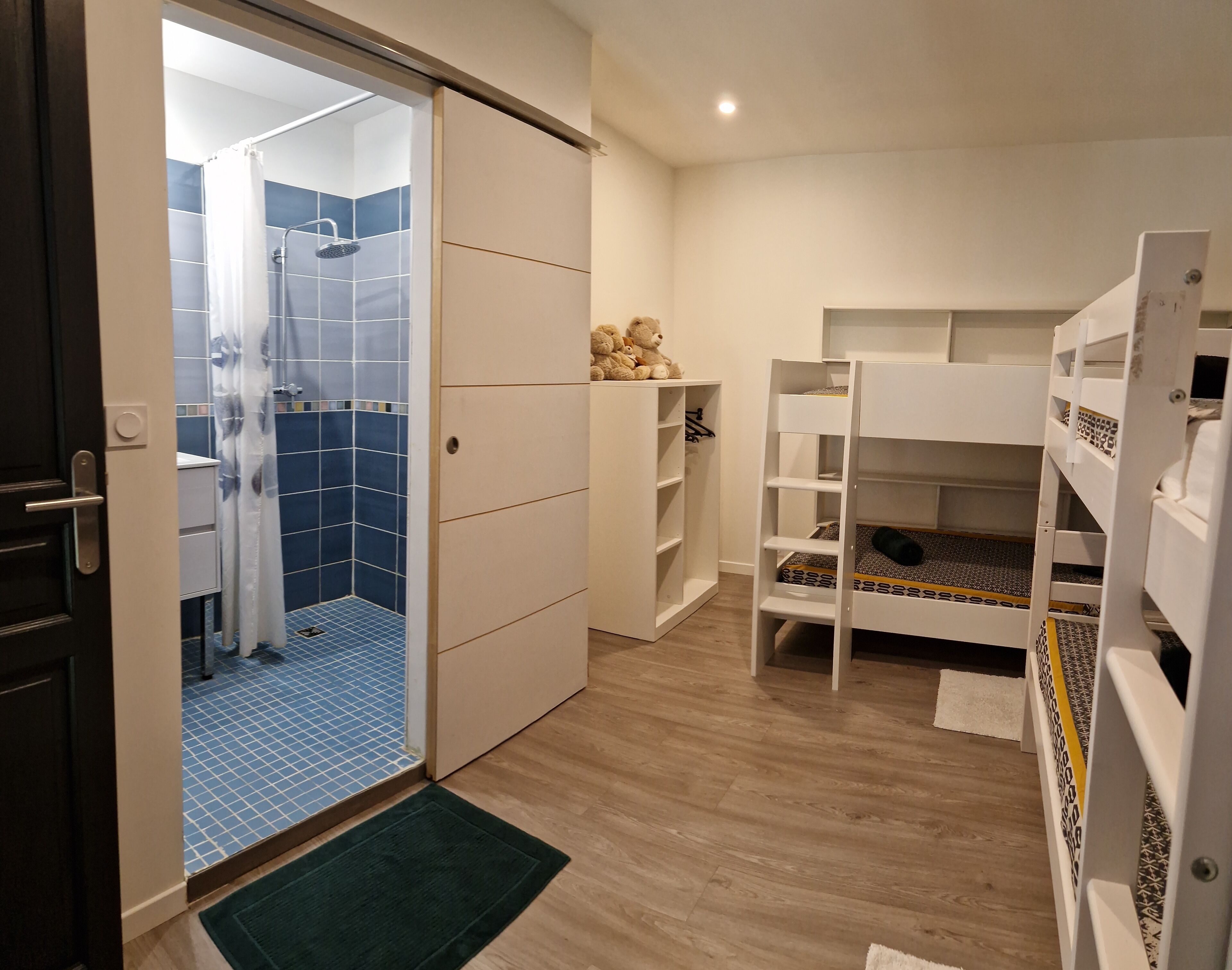A room with a shower area, bunk beds, and a wardrobe.