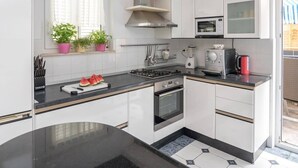 A modern kitchen with white cabinets, a black countertop, a gas stove, a microwave, and a coffee maker.