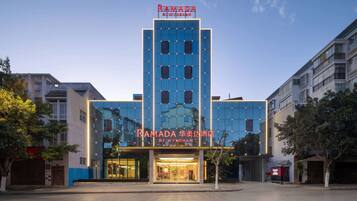 A modern hotel with a prominent sign reading "RAMADA" and "BY WYNDHAM".