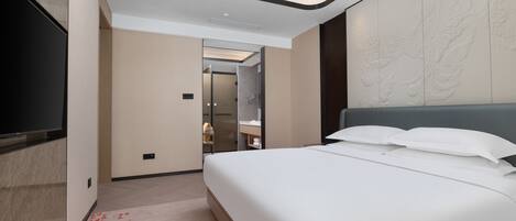 Camera d'albergo moderna con un letto grande, una televisione a schermo piatto e un bagno visibile attraverso una porta aperta.