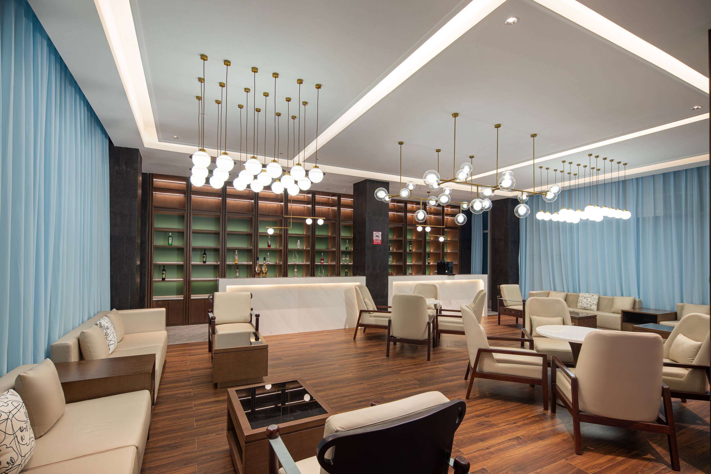 A modern lobby with a reception desk, seating area, and a bar.