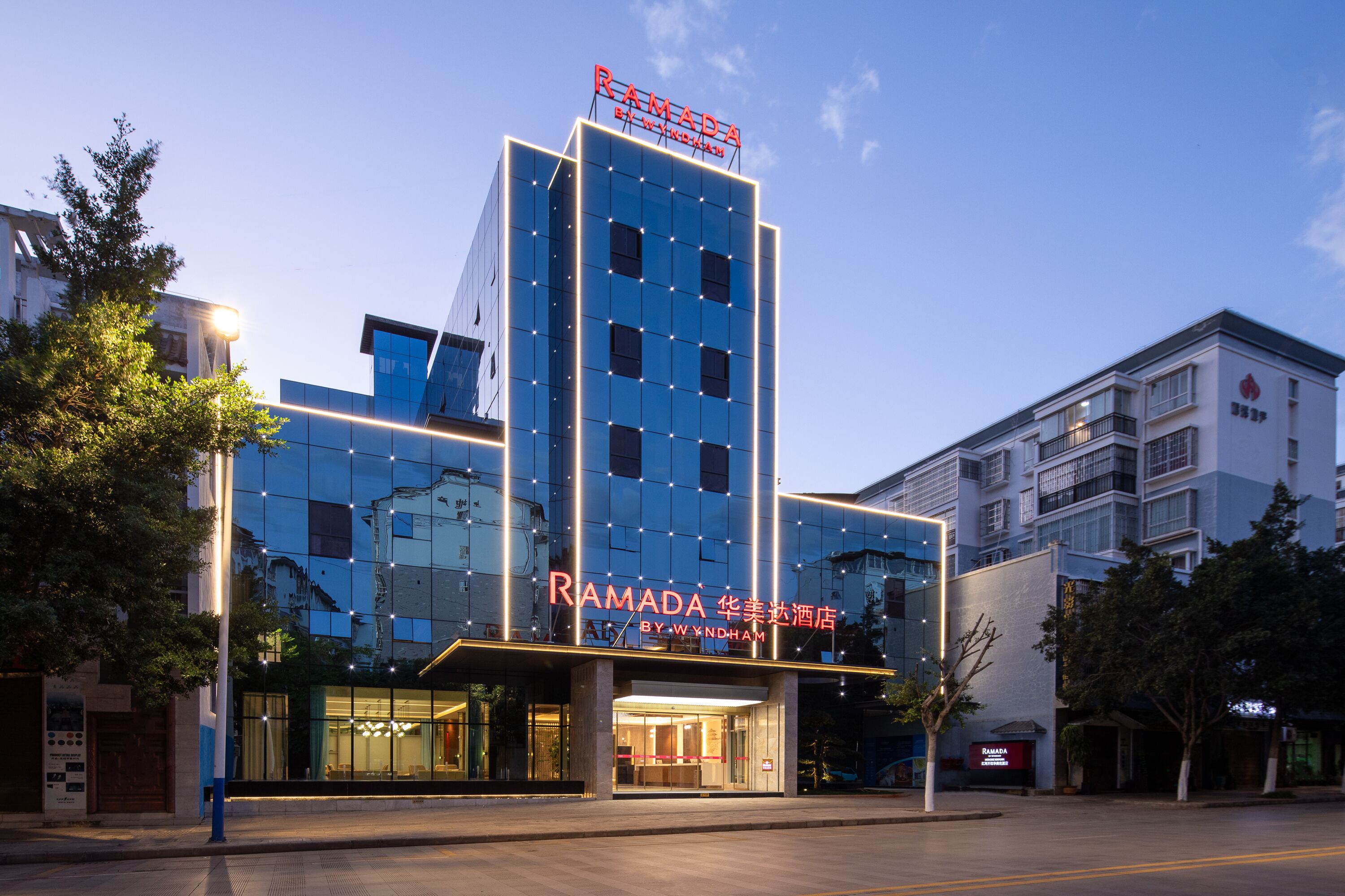 A modern hotel with a prominent sign reading "RAMADA BY WYNDHAM".