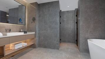 A modern bathroom with a large mirror, a sink, a bathtub, and a vanity with towels.